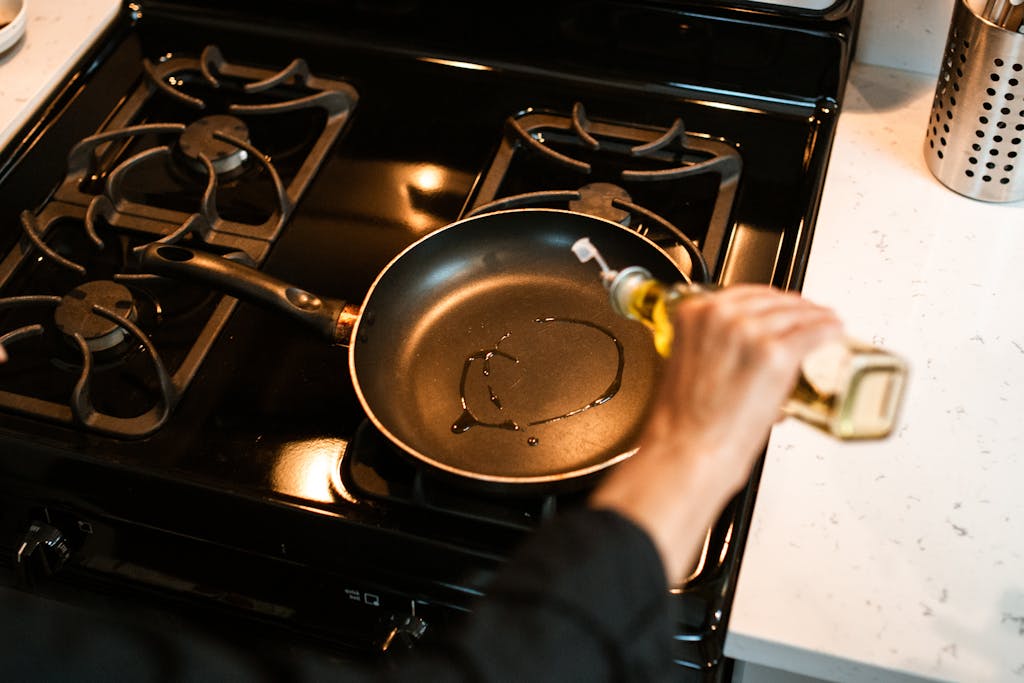 Crop unrecognizable chef pouring oil in frying pan