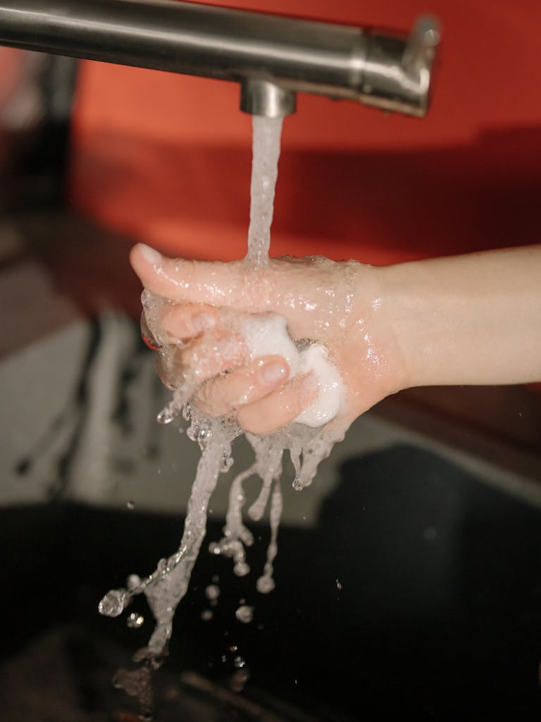 Person Washing Hands on Sink