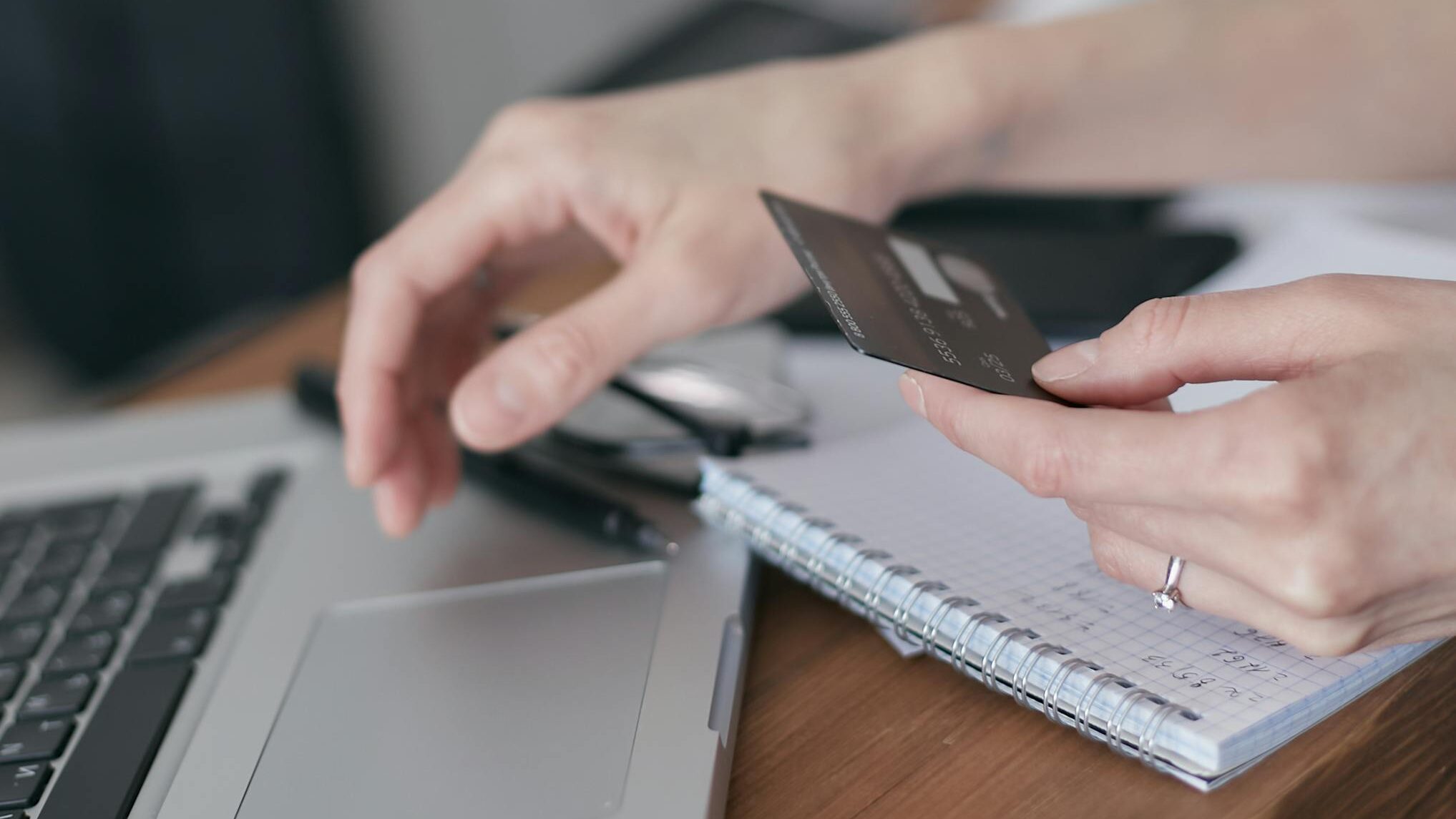 A Person Holding a Credit Card Near a Laptop